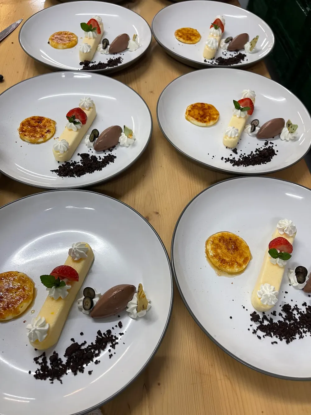 Angerichtete Dessertteller mit Crème brûlée, Cremeriegel, Schokoladenmousse und Erdbeere aus der Küche des Deutschen Hauses