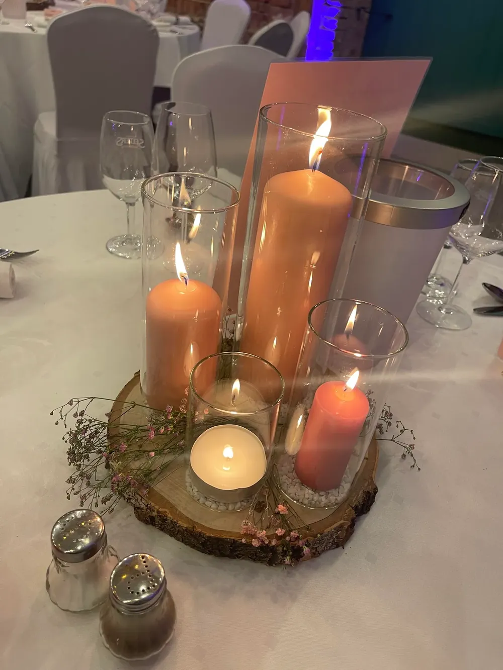 Kerzengruppe in Glaszylindern mit Schleierkraut auf einer Baumscheibe, Tischdekoration am Abend
