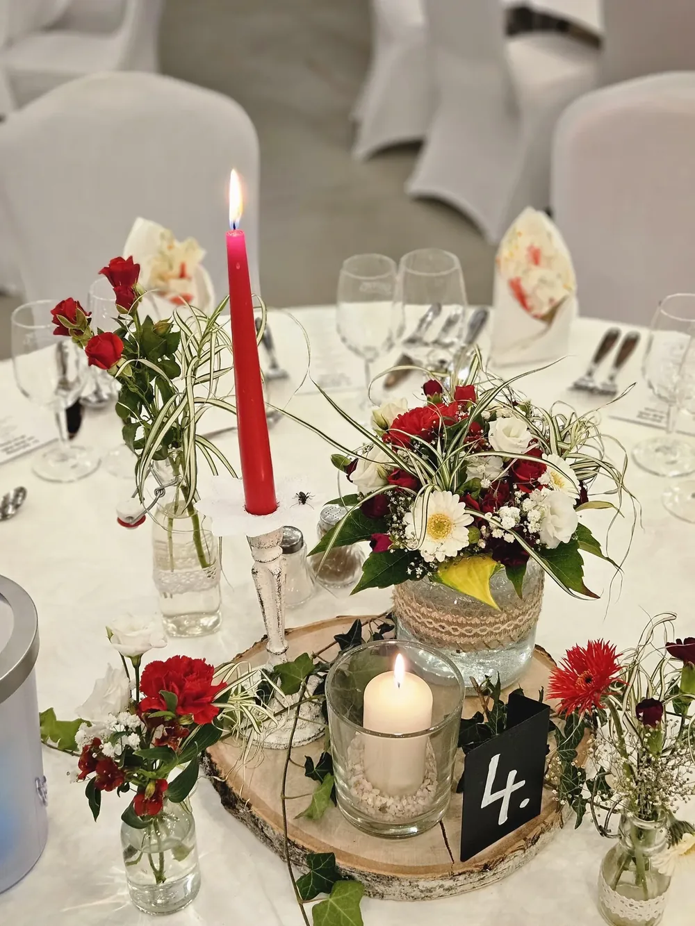 Runder Hochzeitstisch mit roten und weißen Blumen, Kerzenständer, Windlicht und Tischnummer 4