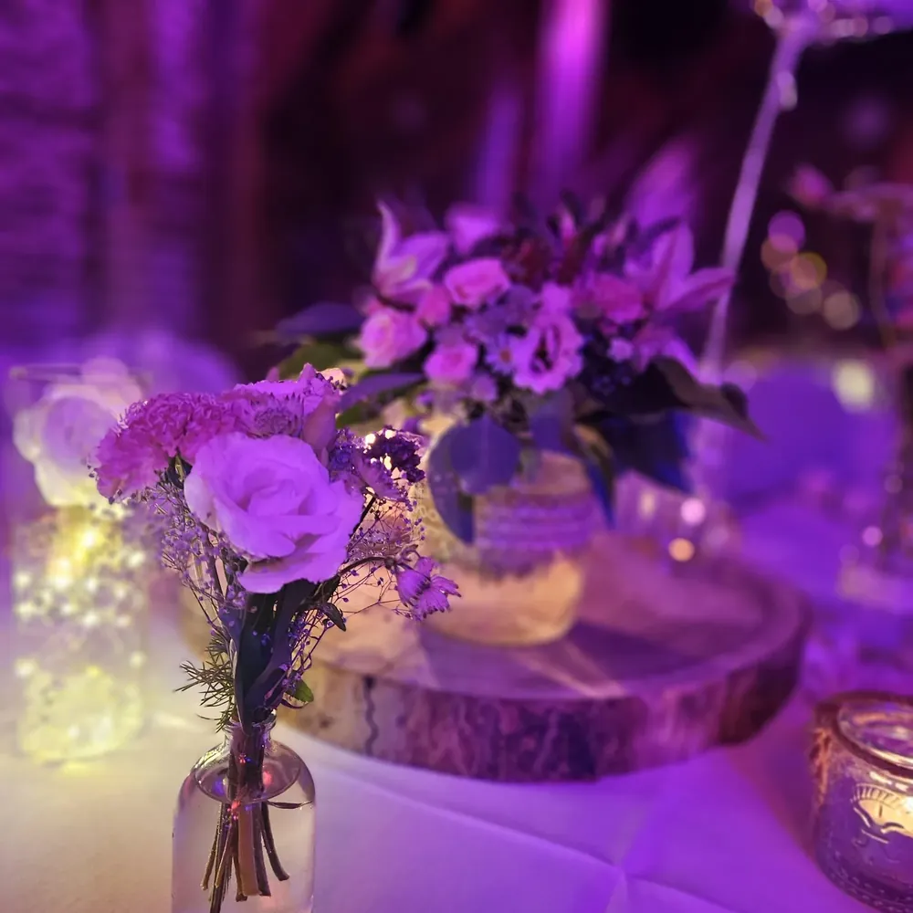 Blumenstrauß und Kerzen in violettem Abendlicht bei einer Feier in der Scheune am Arendsee